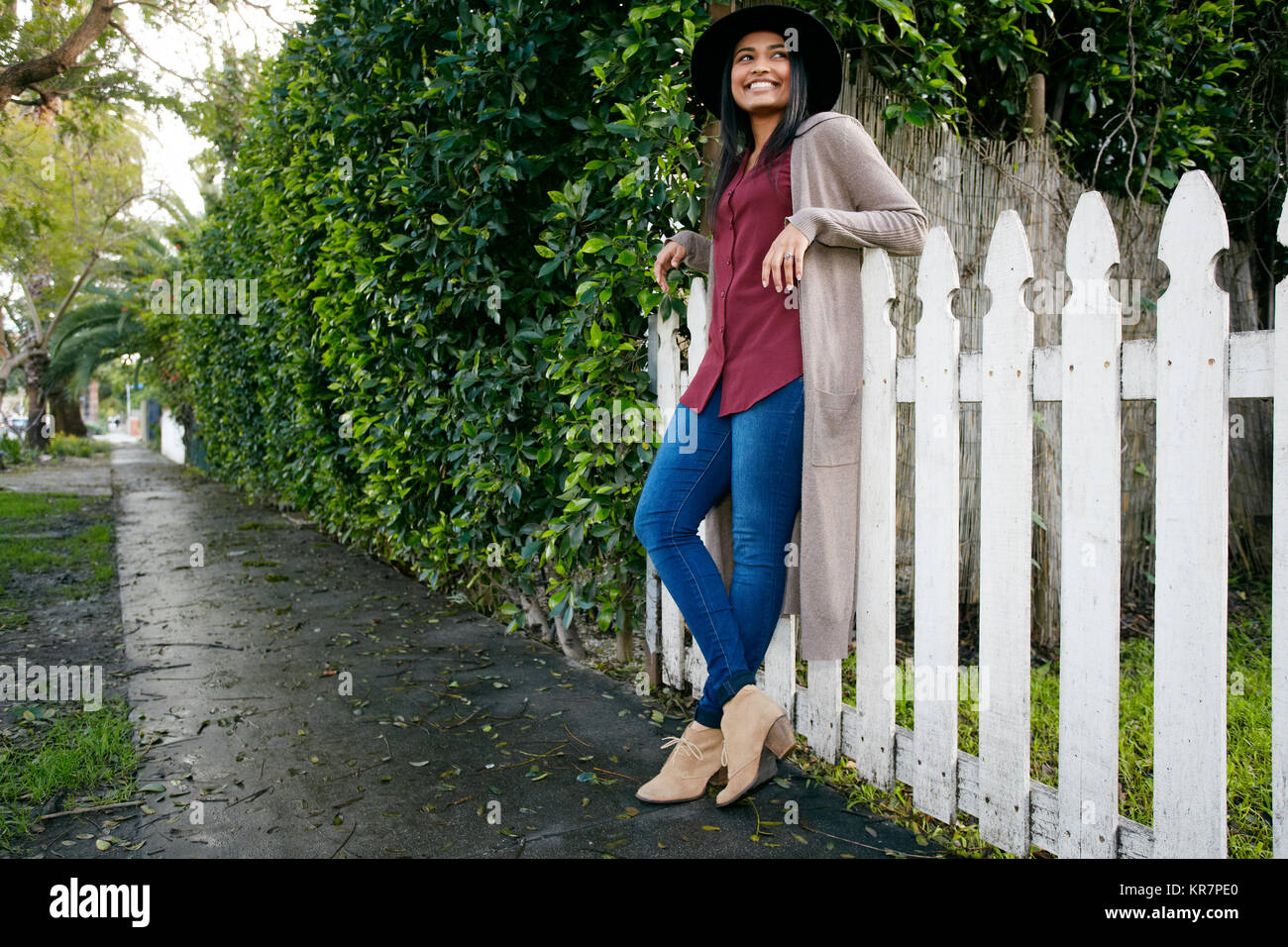 Sorridente razza mista donna appoggiata sul recinto Foto Stock