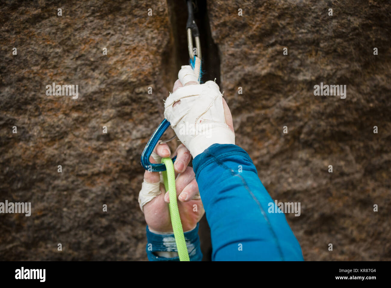 Dettaglio di un uomo clipping nella sua fune ad una di quickdraw durante una arrampicata Foto Stock