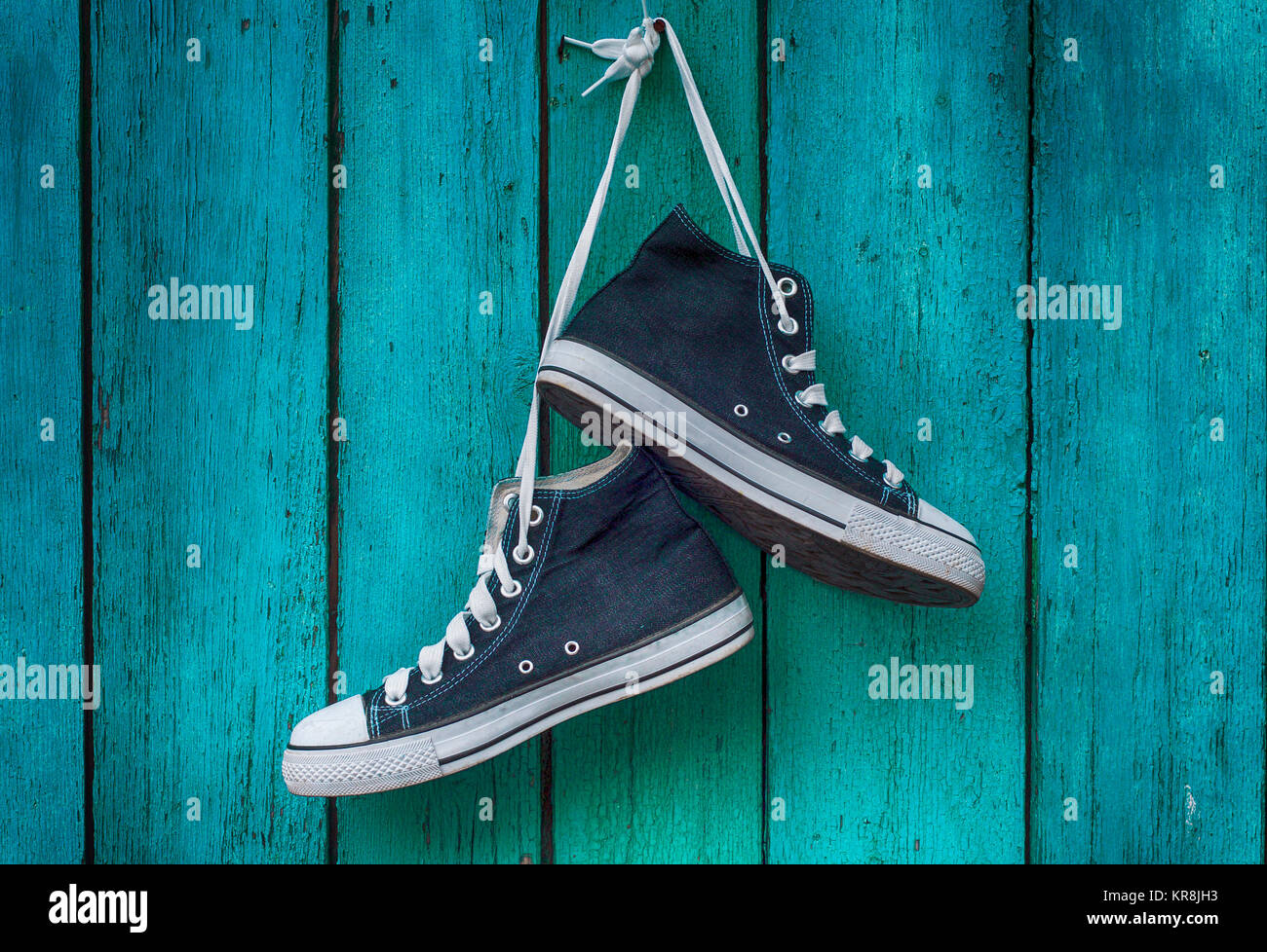 Coppia di Blue Men's sports sneakers appesa a un chiodo sulla parete del vecchio shabby green Foto Stock
