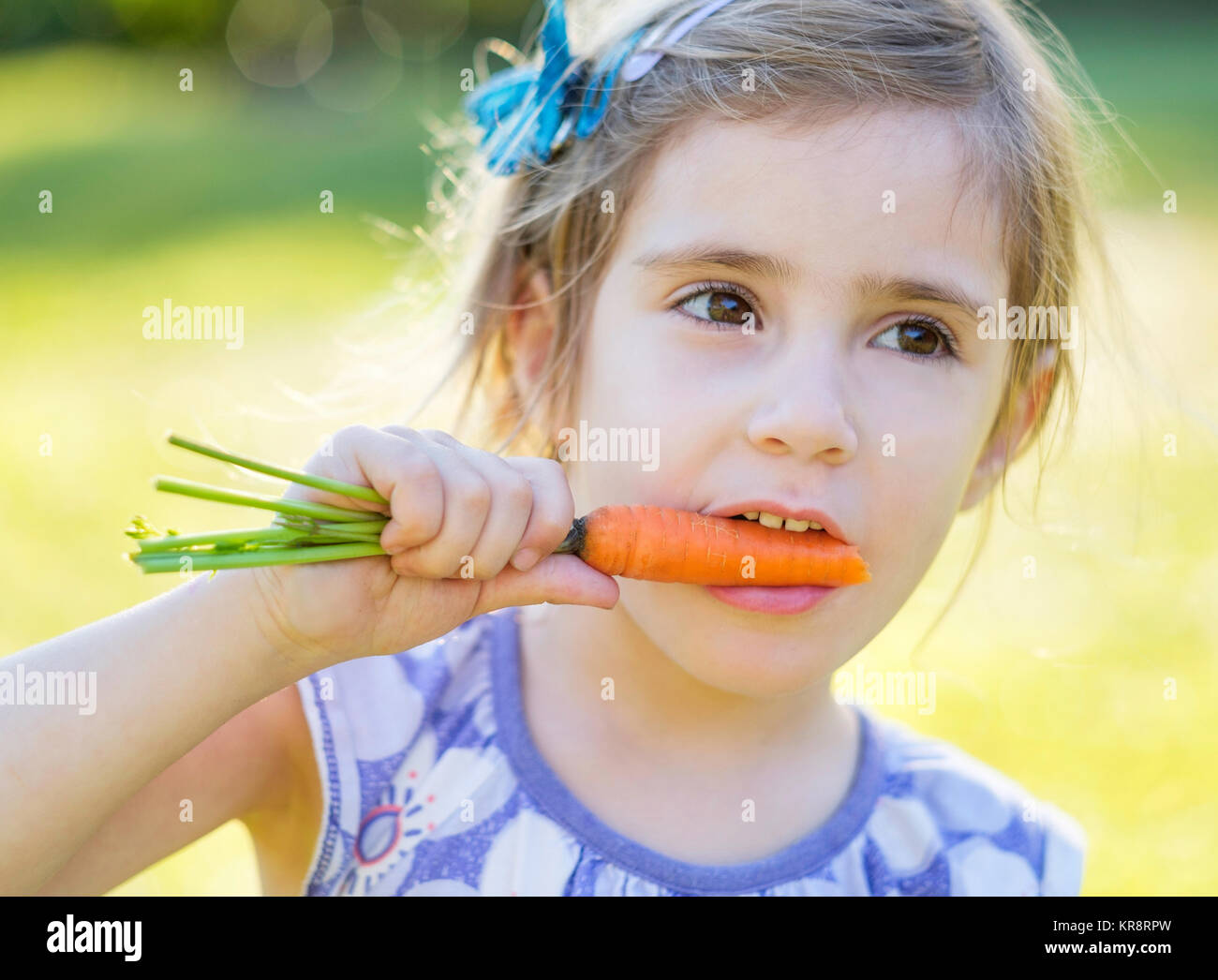 Bambina (4-5) mangiando la carota Foto Stock
