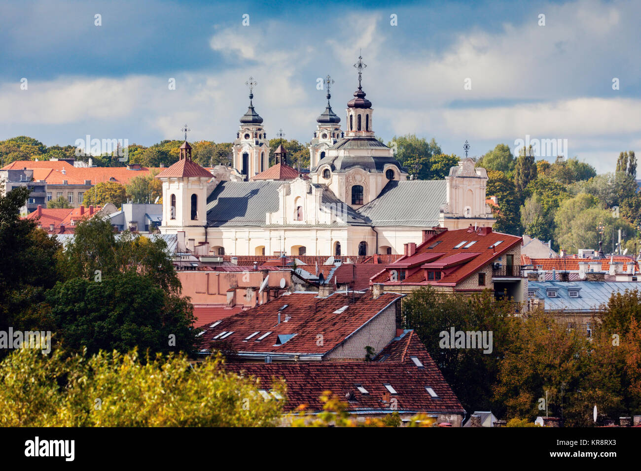 La Lituania, Vilnius, nuvole temporalesche sopra la chiesa e gli edifici residenziali Foto Stock