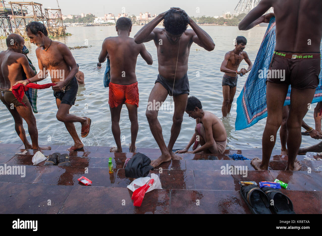 Gli uomini si bagnano al ghats accanto al Fiume Hooghly in Kolkata, India Foto Stock