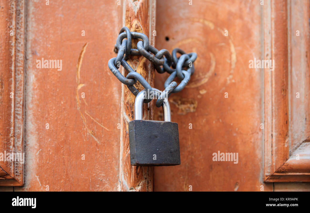 Lucchetto con catena bloccando l'ingresso di una porta di legno. Vista ravvicinata. Foto Stock