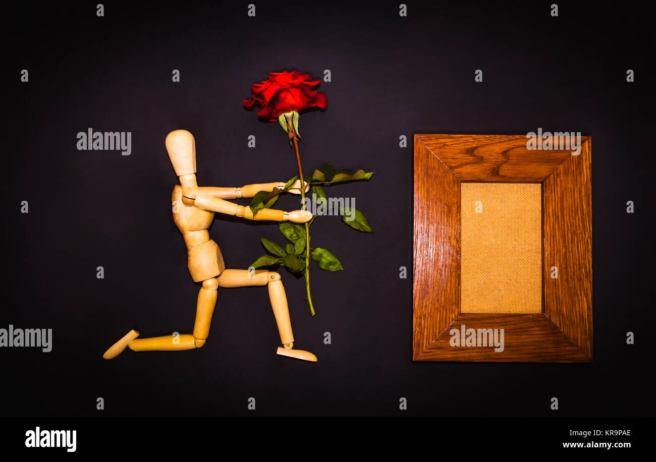 Red Rose e uomo di legno su sfondo nero Foto Stock