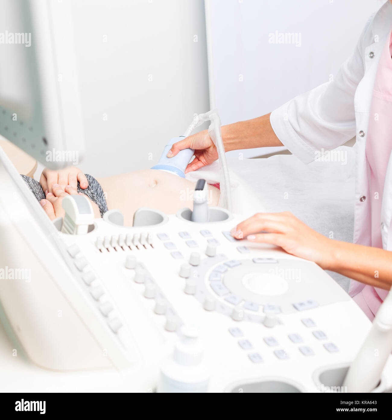 Ecografista la scansione di giovane donna incinta il ventre con trasduttore ultrasonico facendo ecografia ostetrica Foto Stock