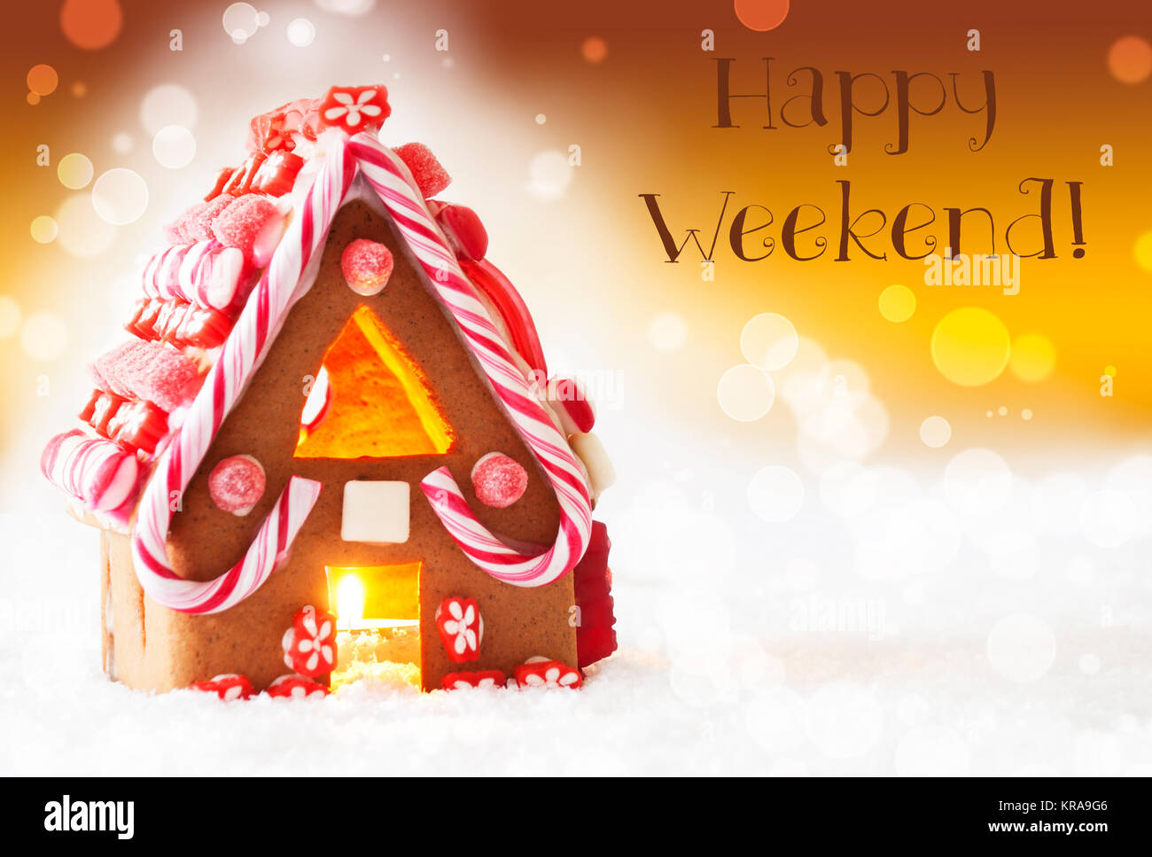 Gingerbread House di scenario innevato come decorazione di Natale. Lume di candela per atmosfera romantica. Sfondo dorato con effetto Bokeh di fondo. Testo inglese Happy Weekend Foto Stock