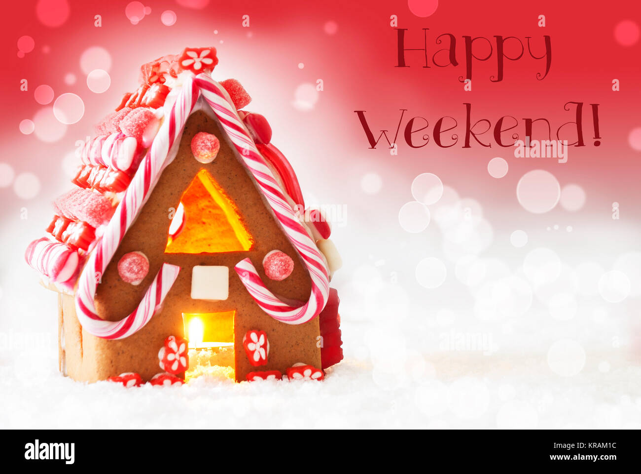 Gingerbread House di scenario innevato come decorazione di Natale. Lume di candela per atmosfera romantica. Sfondo rosso con effetto Bokeh di fondo. Testo inglese Happy Weekend Foto Stock