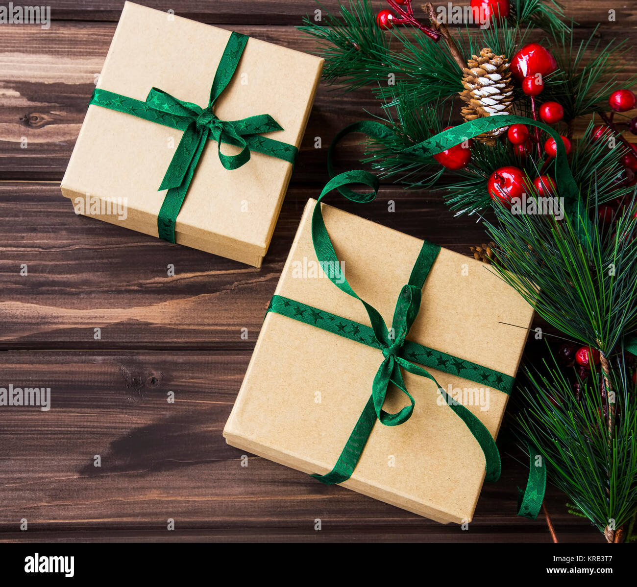 Festive eleganti confezioni regalo decorato con nastro verde e Abete rami e bacche di ornamenti su sfondo di legno Foto Stock