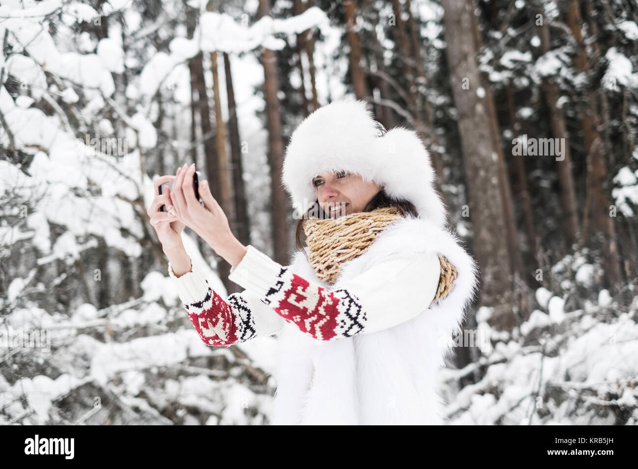 Bella donna è tenuto selfie all aperto in una natura. Alberi innevati in background Foto Stock