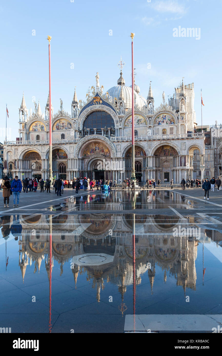 Basilica di San Marco si riflette in Acqua Alta o eccezionale alta marea, Piazza San Marco, Venezia, Italia con i turisti in una giornata di sole Foto Stock