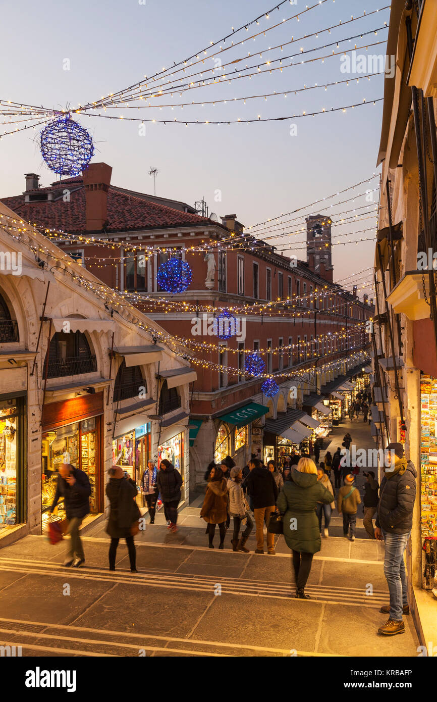 Le luci di Natale e gli acquirenti sul Ponte di Rialto, San Polo, Venezia, Italia guardando giù le fasi al crepuscolo Foto Stock