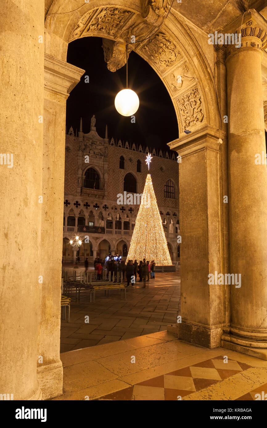 Il LED conico albero di Natale in Piazza San Marco, Venezia, Italia, di fronte al Palazzo dei Dogi osservata attraverso un arco con un tour di gruppo roun raccolti Foto Stock