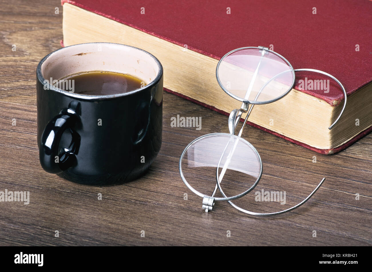 Una tazza di caffè con un libro e eyeglasses.education, apprendimento, la lettura o la mattina di buon concetto. Primo piano Foto Stock