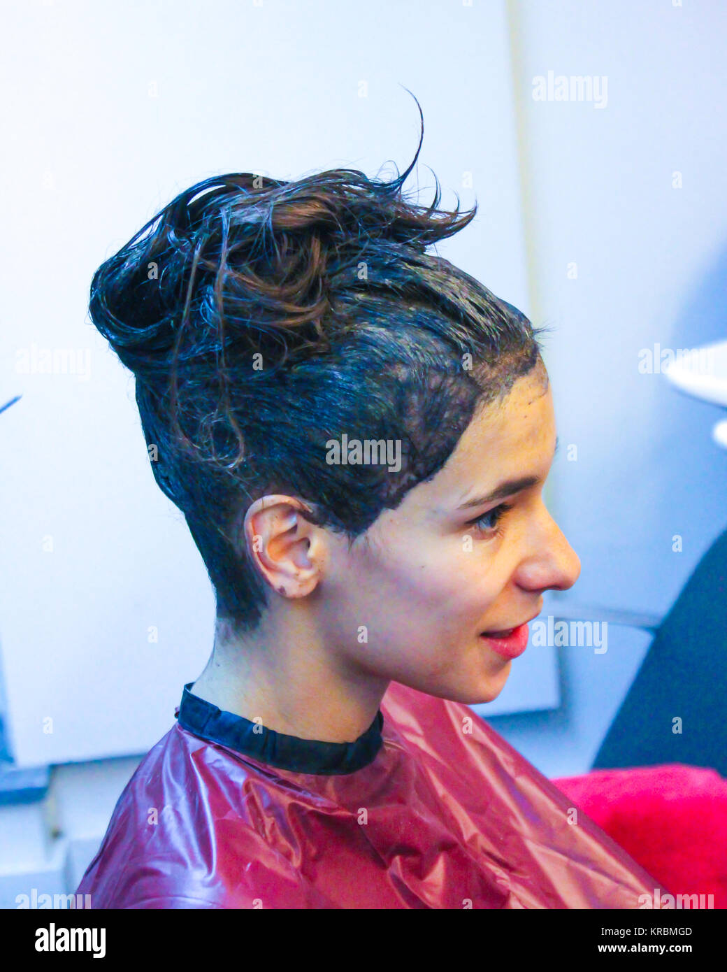 La donna ha i capelli appena stato dipinto attende per la verniciatura a effetto prima del lavaggio in seduta dal parrucchiere coperti con una rosa il coperchio in plastica Foto Stock