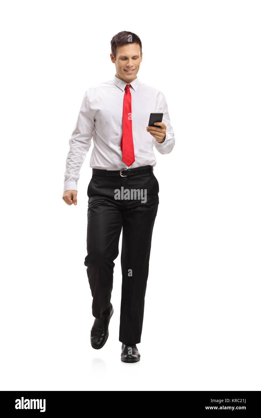 A piena lunghezza Ritratto di un elegante guy camminare e utilizzando un telefono isolato su sfondo bianco Foto Stock