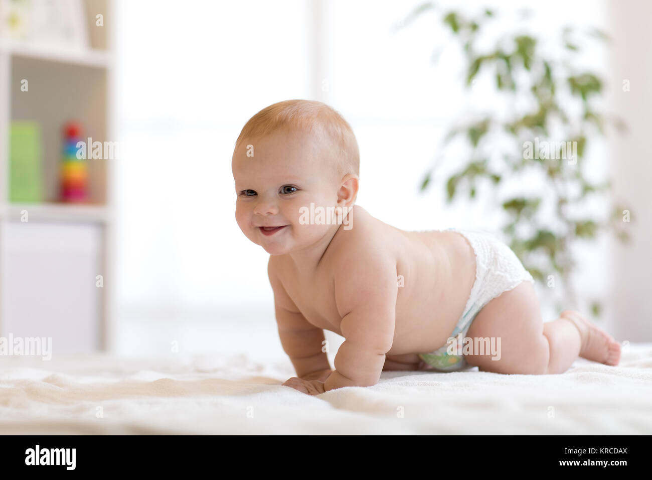Funny baby boy strisciando sul letto di casa Foto Stock