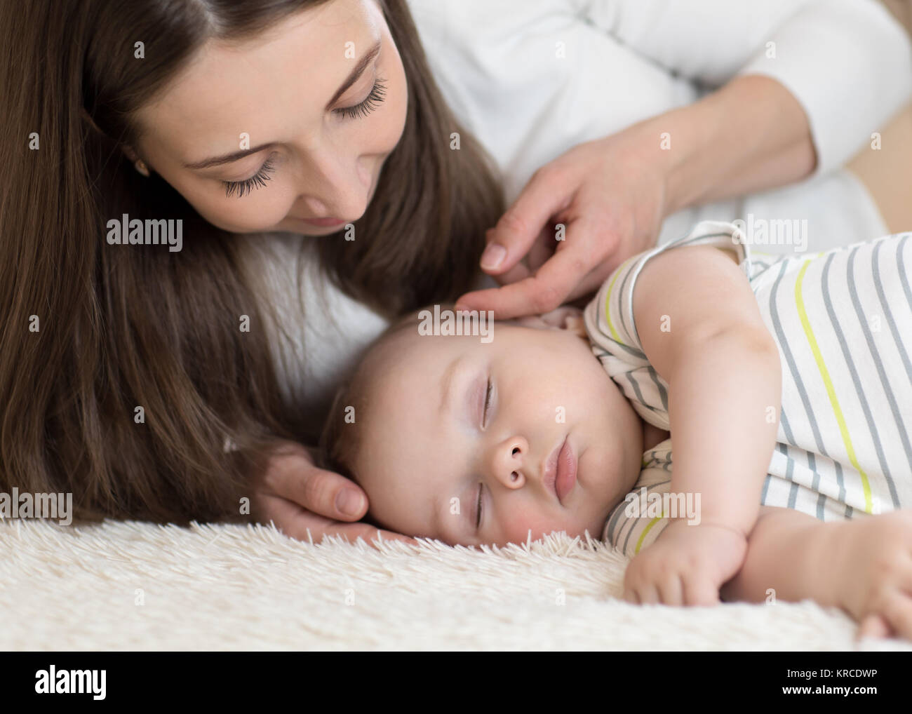 Bella giovane mamma guarda al bambino dorme nel letto di casa Foto Stock