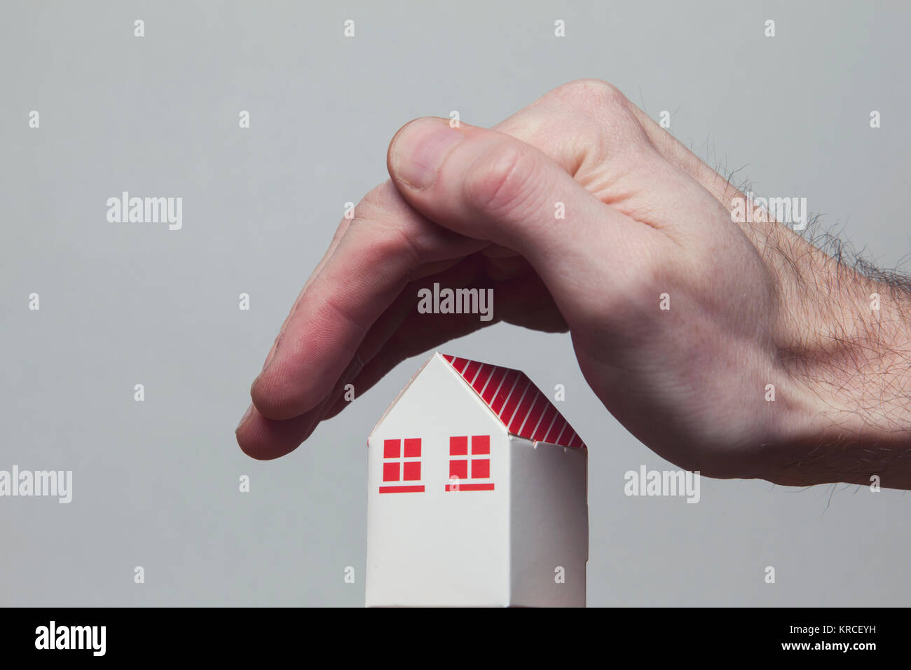 Mani che coprono un giocattolo di casa. Home il concetto di protezione Foto Stock