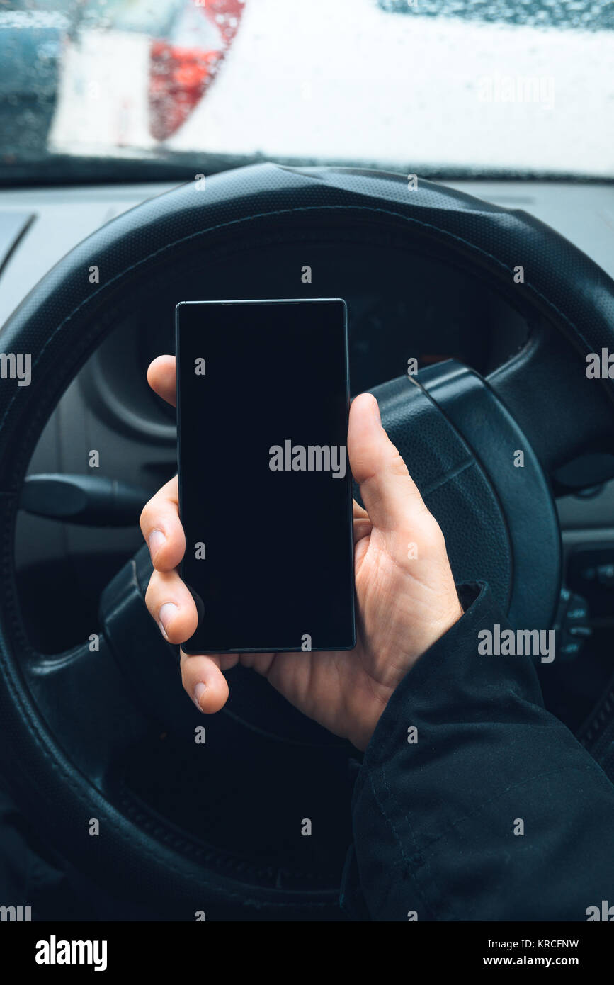 L'uomo utilizza lo smartphone in auto con schermo vuoto del telefono mobile device come spazio di copia Foto Stock