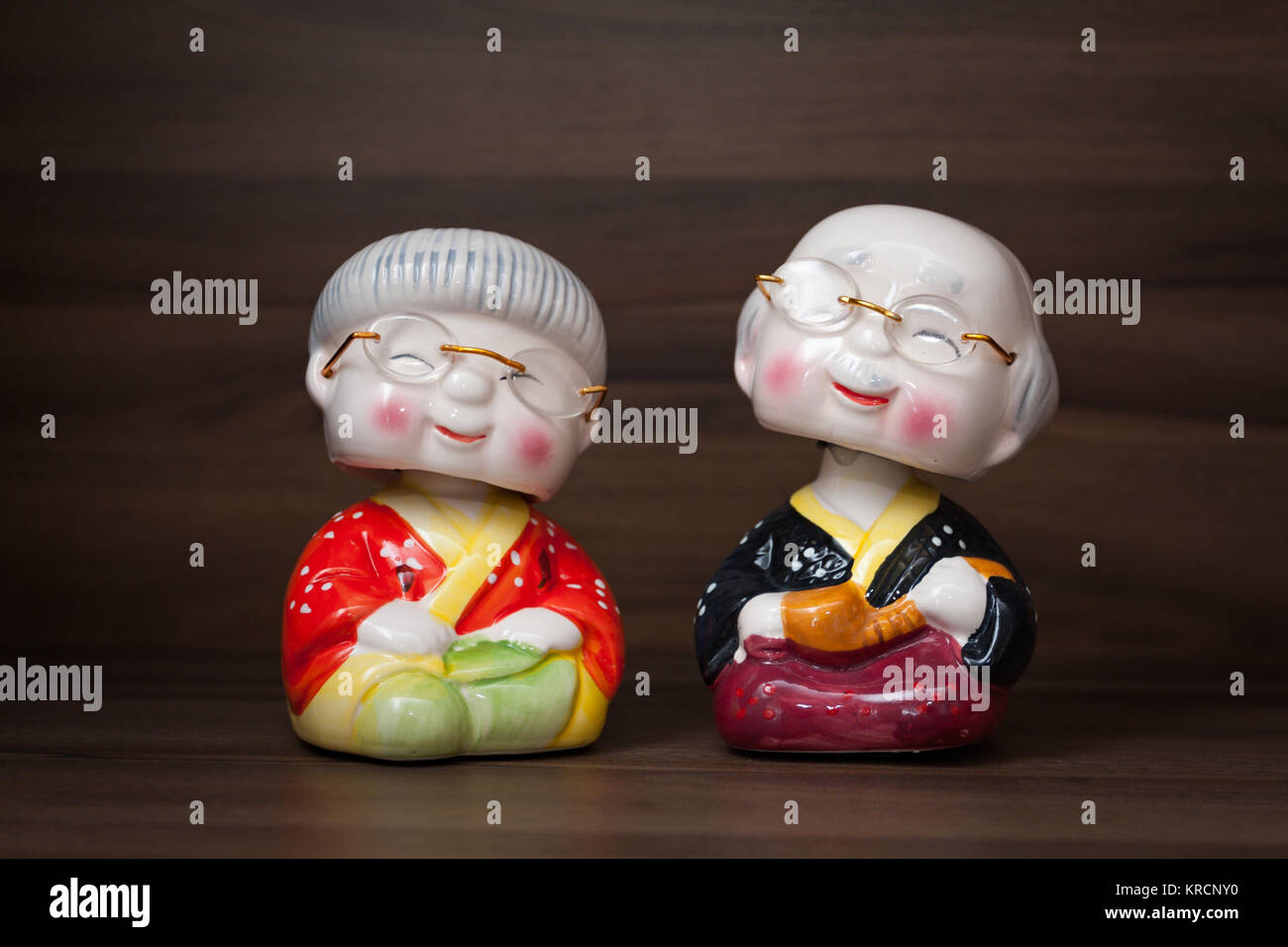 Giapponese carino la nonna e il nonno bobble testa postura seduta figure in miniatura contro lo sfondo di legno Foto Stock