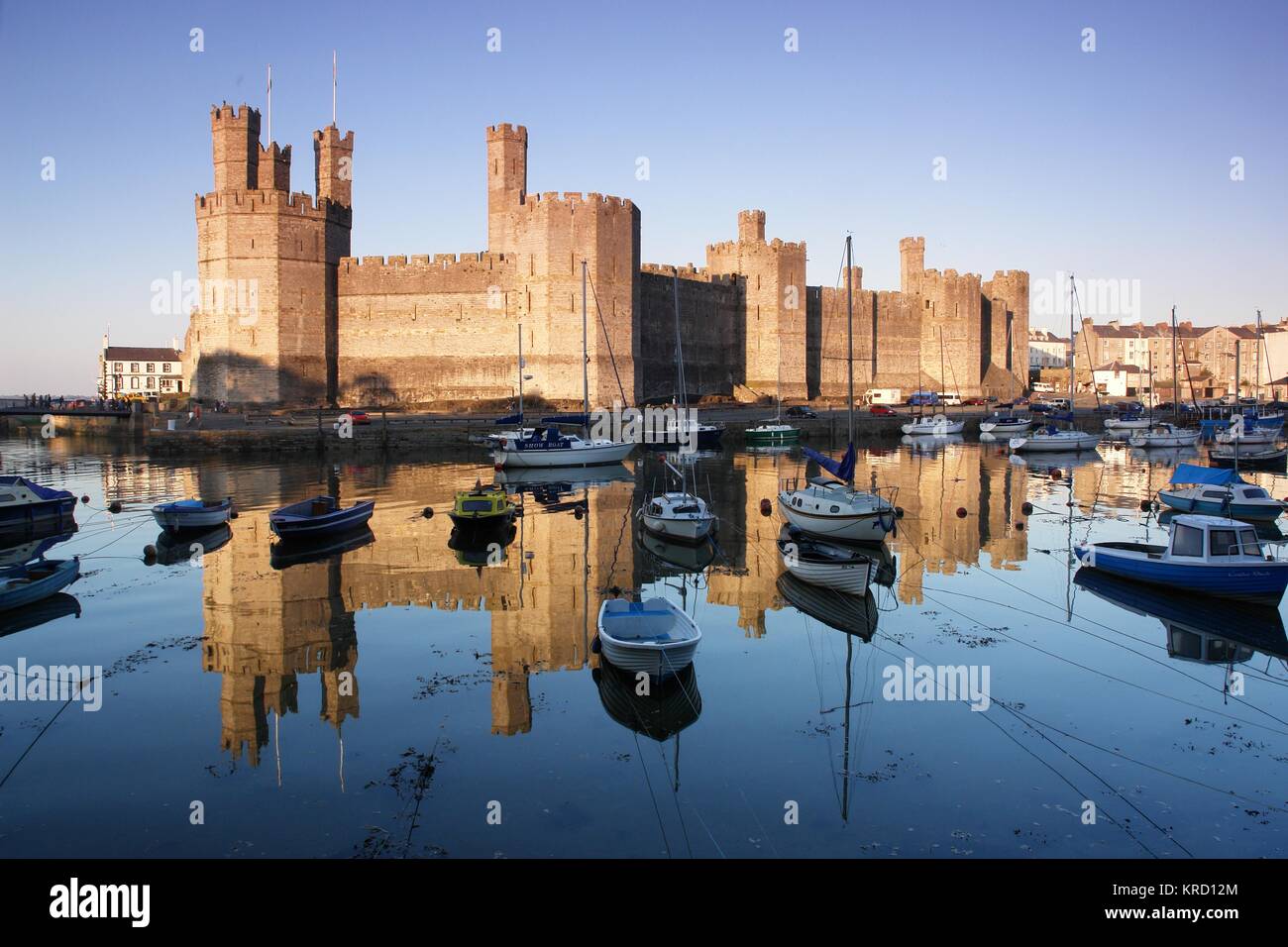 Una vista impressionante del castello di Caernarfon (Caernarvon) nel Gwynedd, Galles del Nord, con numerose barche in acqua in primo piano. Il castello fu costruito dal re inglese Edoardo i intorno al 1283, sul sito di una fortezza romana e Norman motte. Foto Stock