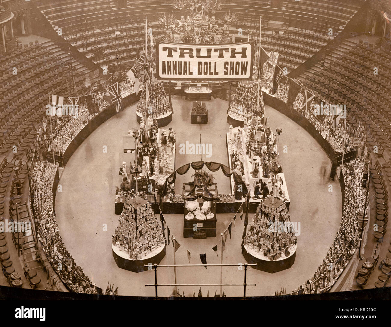 L'arena della Royal Albert Hall di Londra con un display di grandi dimensioni di bambole con sedi vuote a tutto tondo. Sopra l'arena è un banner di proclamare la verità bambola annuale mostra. Data: circa 1909 Foto Stock
