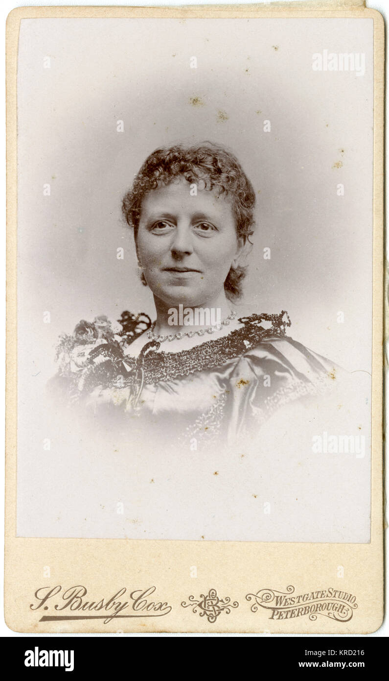 Un sorridente donna vittoriana in una testa e spalle ritratto. Indossa un abito in raso con rifinitura intorno al collo e una collana. Data: circa 1880 Foto Stock