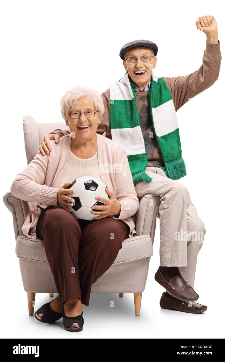 Allegro anziani appassionati di calcio con un campo di calcio e un foulard seduto in poltrona isolati su sfondo bianco Foto Stock