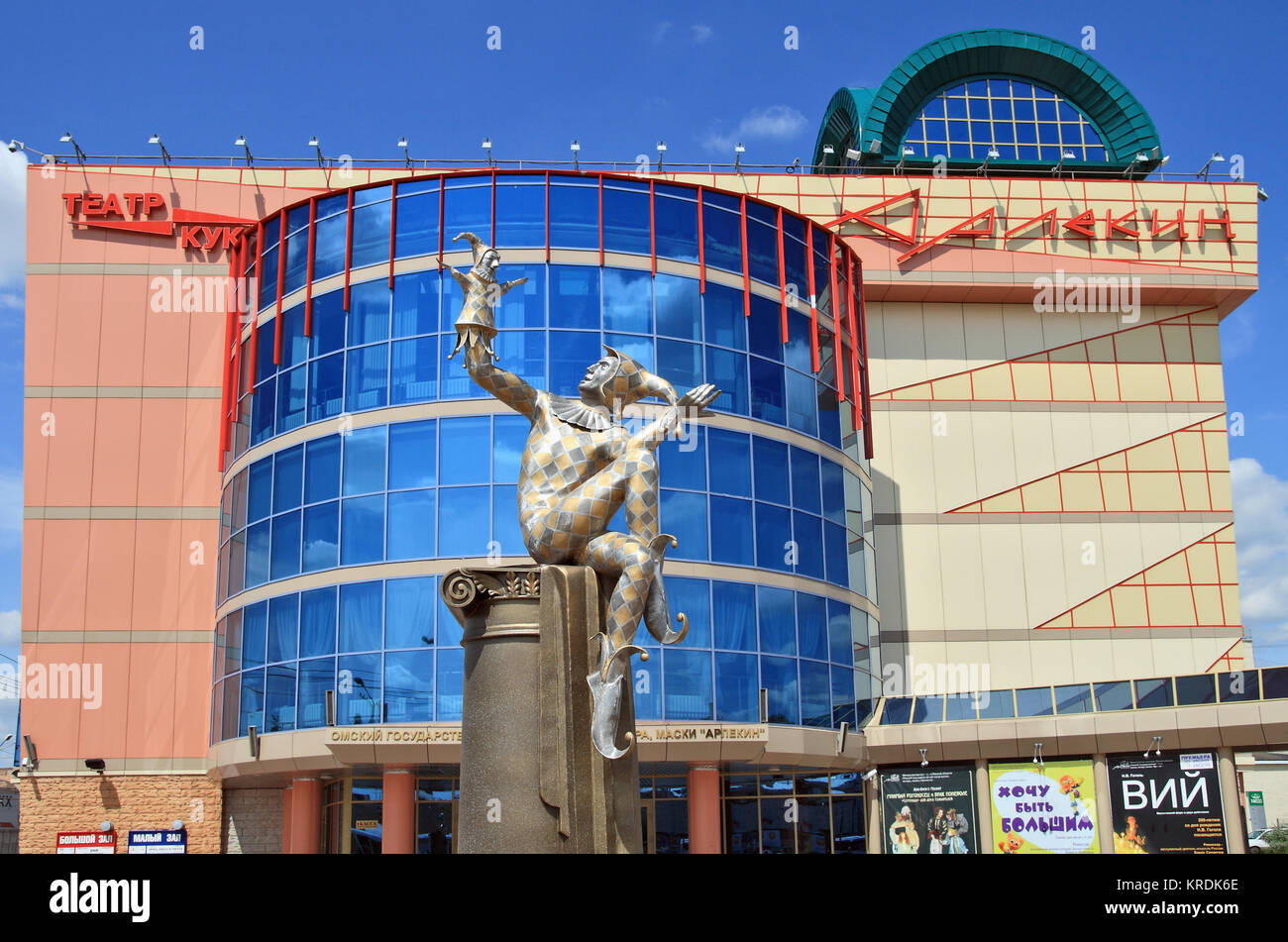 Editoriale.Omsk, Russia Juiy 02, 2009 Omsk stato teatro di burattini, attore, maschera Arlecchino su Carl Marx street. e scultura davanti alla facciata di Foto Stock