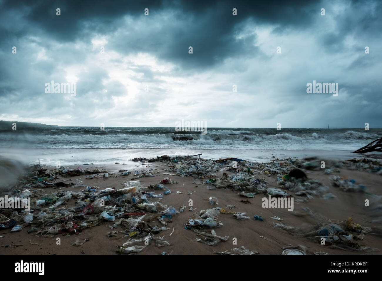 Immondizia sulla spiaggia, inquinamento ambientale in Bali Indonesia. Tempesta è venuta su sfondo. E gocce di acqua sono sulla lente della fotocamera. Drammatica vista Foto Stock