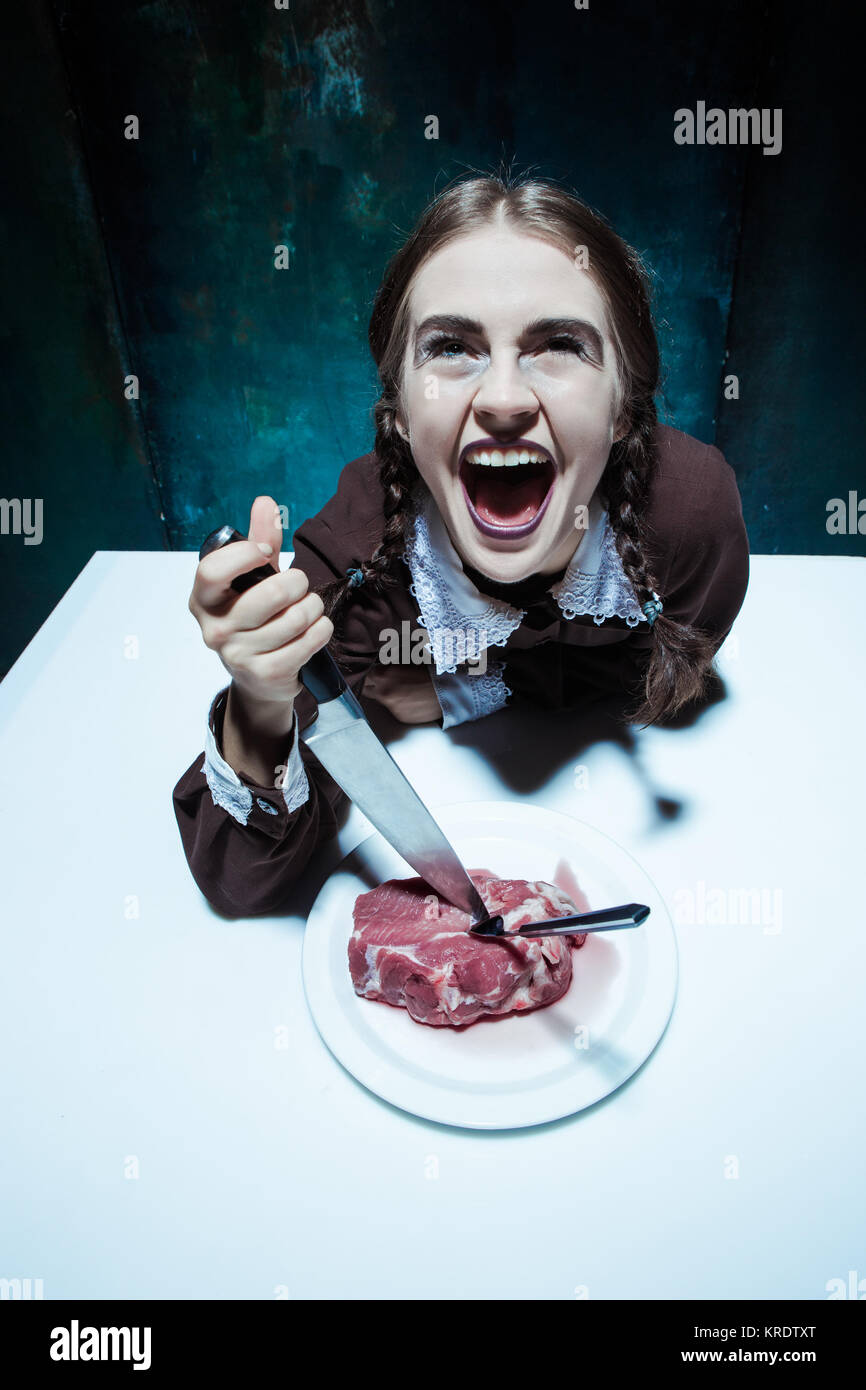 Bloody Halloween tema: crazy ragazza con un coltello, forchetta e carne Foto Stock