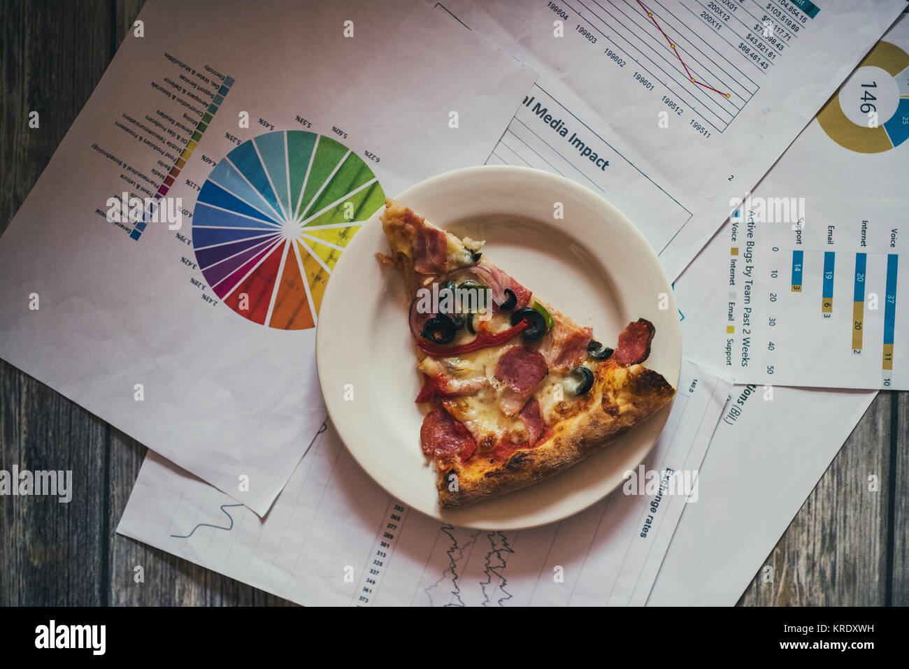 Un trancio di pizza nei pressi di grafici - pausa di lavoro Foto Stock