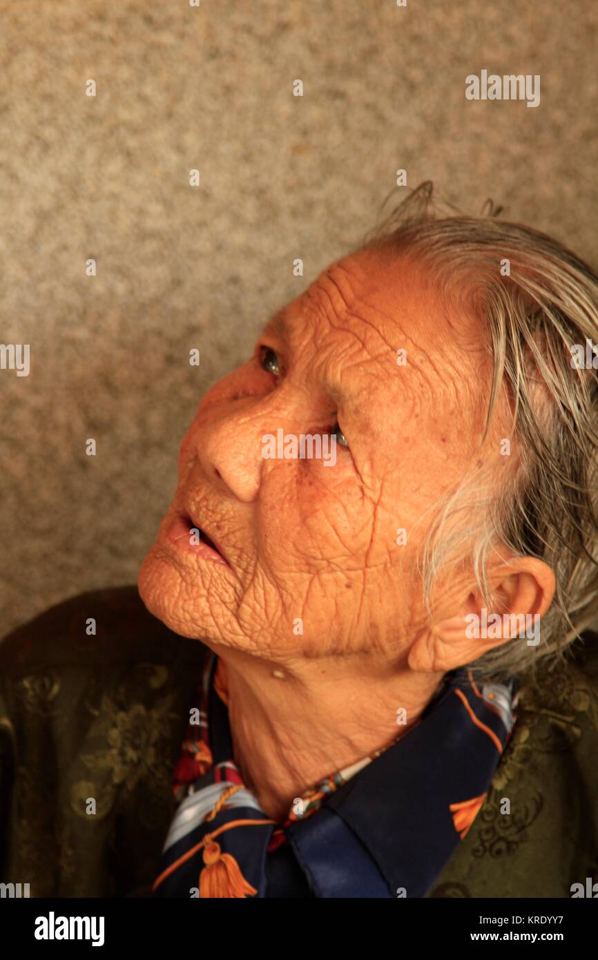 97 anni donna vietnamita il suo lavoro in stallo un lungo il delta del Mekong Il mercato bagnato, Vietnam Foto Stock