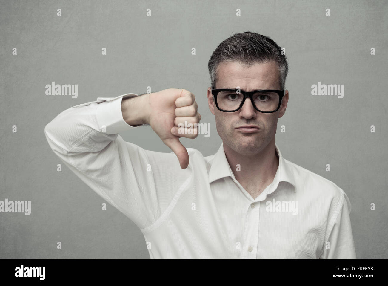 Uomo deluso dando un pollice in giù e guardando la telecamera, antipatia e concetto disapprovement Foto Stock