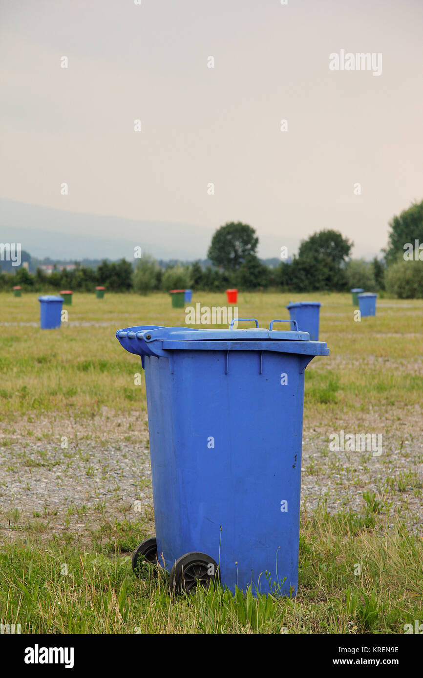 ampio prato destinato al parcheggio con bidoni colorati per la raccolta dei rifiuti Foto Stock