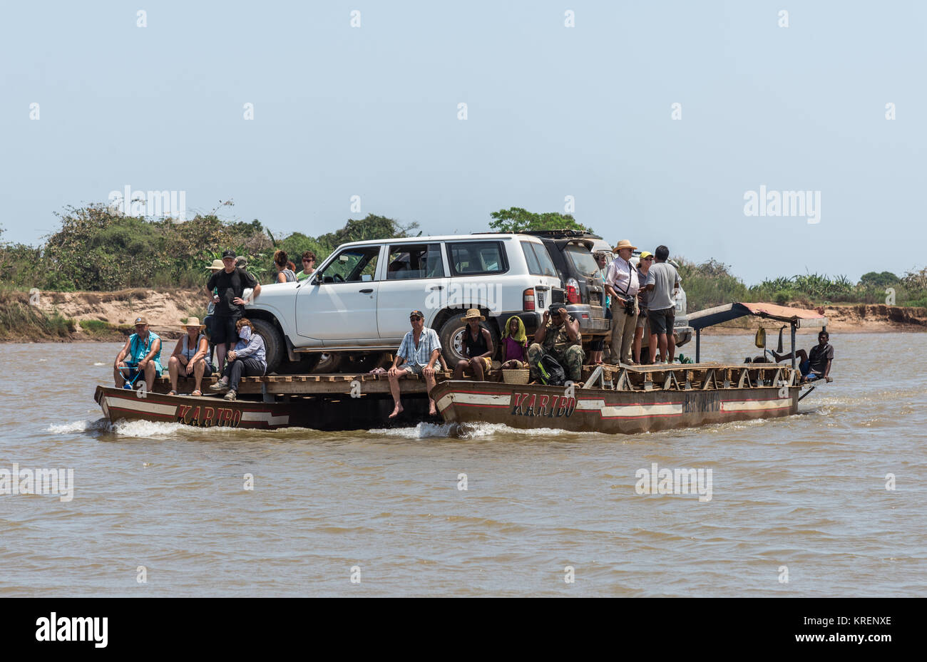 I suv e i passeggeri a bordo di una barca di traghetto sul Fiume Mania. Madagascar, Africa. Foto Stock