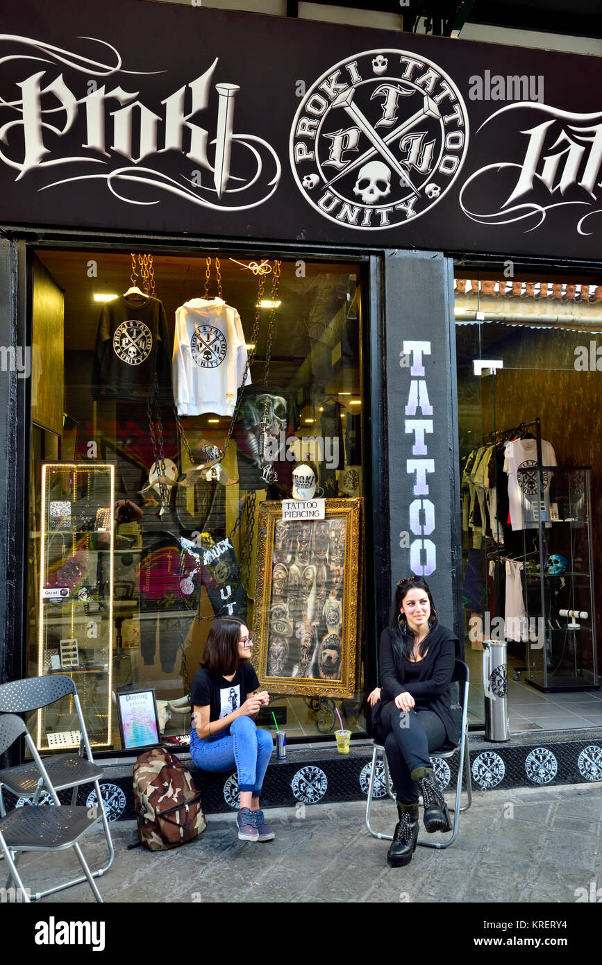 Due donne sedute fuori nella parte anteriore del salotto tattoo Monstiraki area del centro di Atene, Grecia Foto Stock