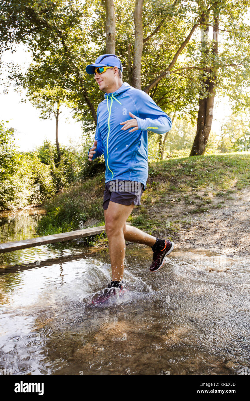 Giovane uomo fare jogging a boschi Foto Stock