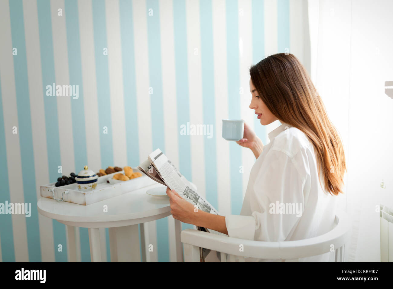 Giovane donna con tazza di caffè seduti a tavola Foto Stock