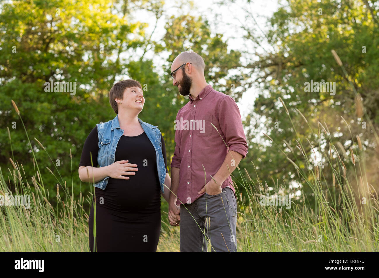 Uomo e di una donna in stato di gravidanza in un campo in Oregon mentre la ragazza è nel suo terzo trimestre. La coppia è sposata e il marito e la moglie sono in attesa Foto Stock
