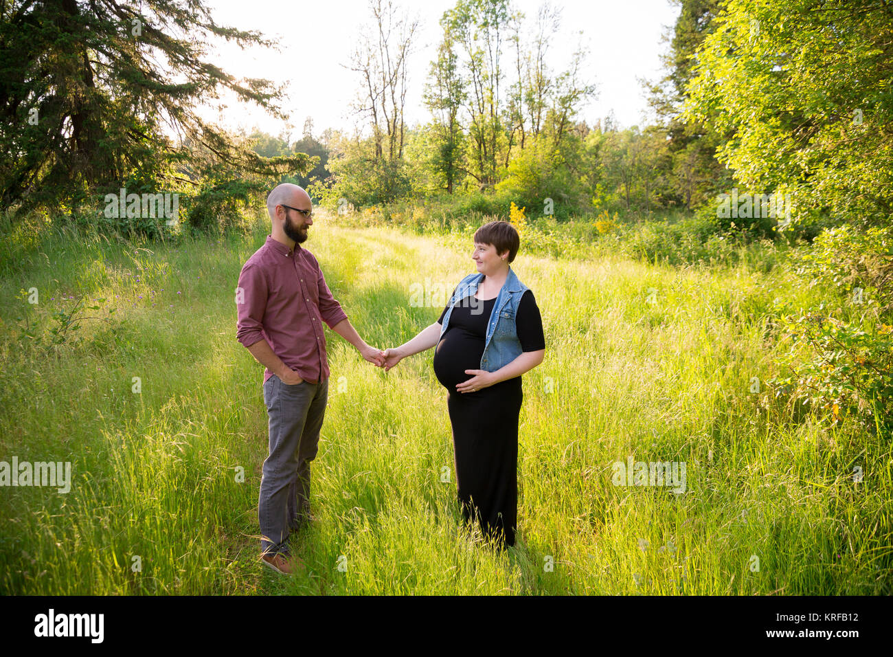 Uomo e di una donna in stato di gravidanza in un campo in Oregon mentre la ragazza è nel suo terzo trimestre. La coppia è sposata e il marito e la moglie sono in attesa Foto Stock