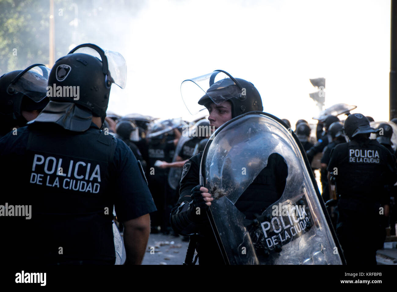 Dicembre 18, 2017 - Buenos Aires, Ciudad AutÃ³noma de Buenos Aires, Argentina - Schermo incrinato, un funzionario stanco tira dietro le linee di polizia. I manifestanti da vari di sinistra dei gruppi attaccati polizia dopo una gran dimostrazione pacifica al di fuori della nazione di edifici del Congresso. Il disegno di legge sono state protestando ""una revisione del sistema pensionistico''"è diventata legge la mattina seguente. Credito: SOPA/ZUMA filo/Alamy Live News Foto Stock