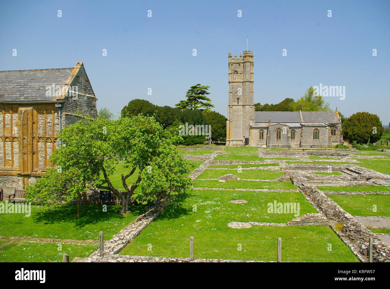Vista dell'abbazia di Muchelney (a sinistra), un edificio classificato di grado i nel villaggio di Muchelney, Somerset, con la chiesa parrocchiale di San Pietro e San Paolo in lontananza sulla destra. Osservando i resti scavati dell'abbazia, risalenti all'epoca medievale. Foto Stock