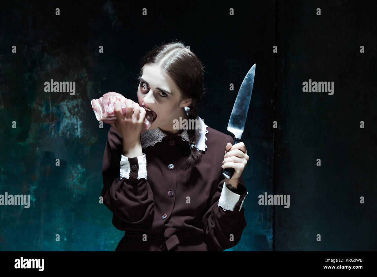 Bloody Halloween tema: crazy ragazza con un coltello e la carne cruda Foto Stock