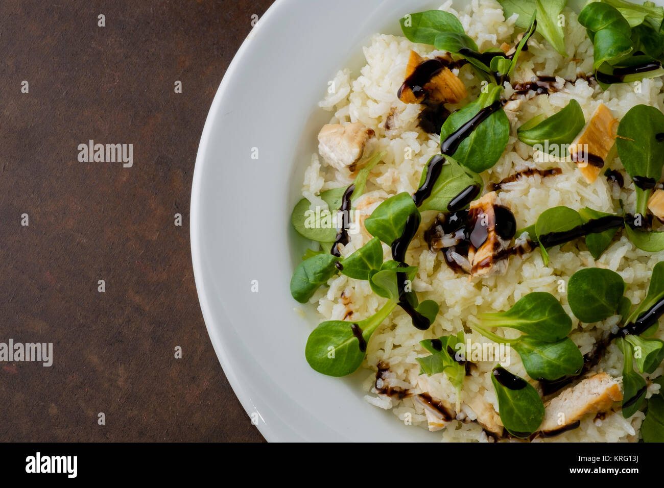 Pollo e riso con insalata di valeriana e aceto balsamico in un piatto sul  tavolo in legno Foto stock - Alamy