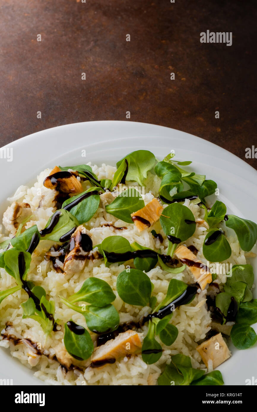 Pollo e riso con insalata di valeriana e aceto balsamico in un piatto sul  tavolo in legno Foto stock - Alamy