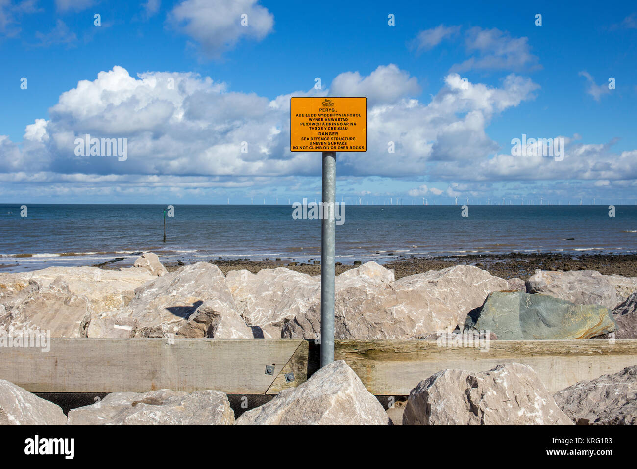 Avviso di pericolo di segno per la difesa del mare struttura superficiale irregolare. Non salire sulla o sulle rocce vicino a Llanddulas North Wales UK Foto Stock