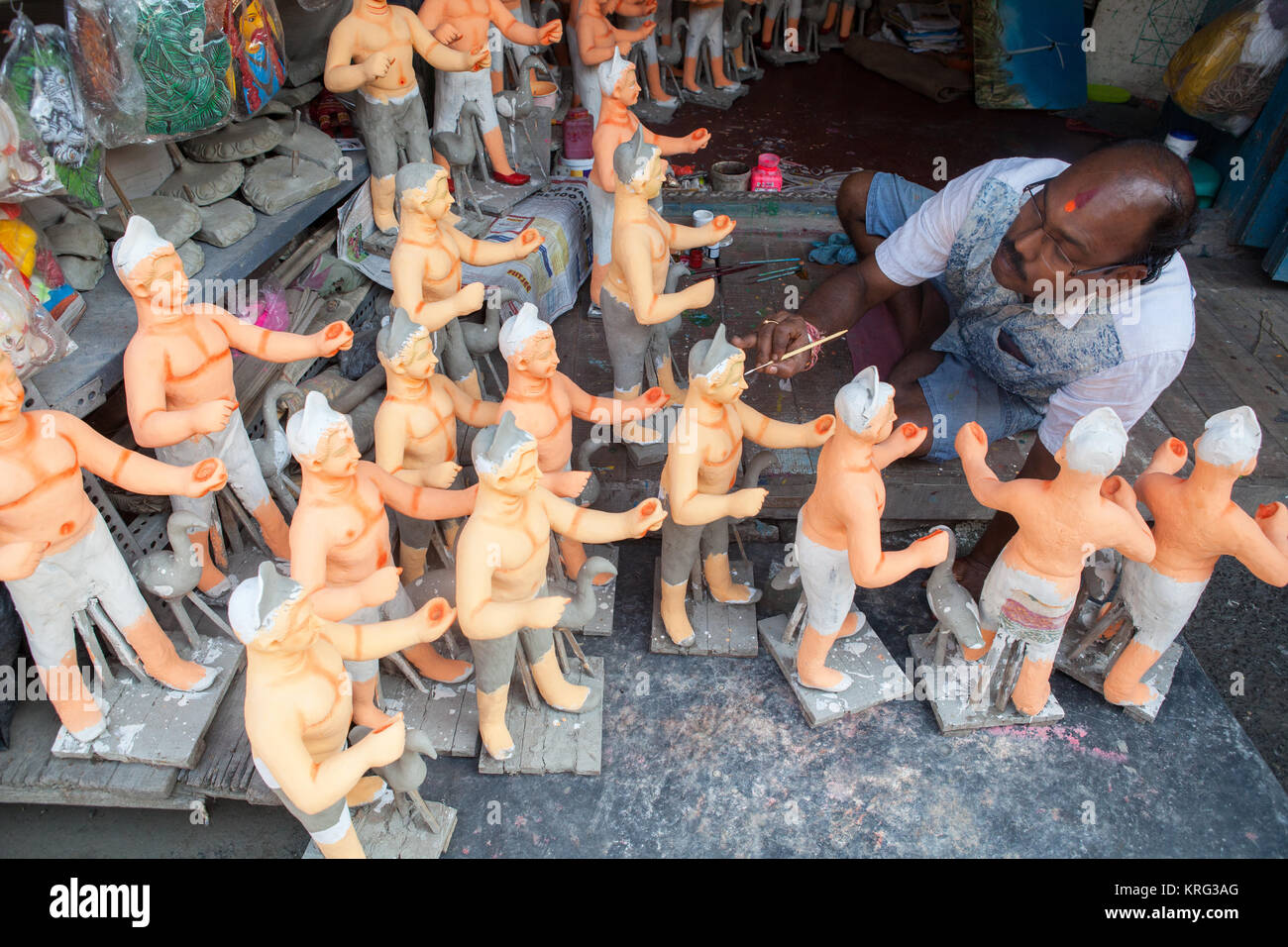 Un pittore di aggiungere colore a Durga idoli nel quartiere di ceramiche di Kumartuli in Kolkata, India Foto Stock