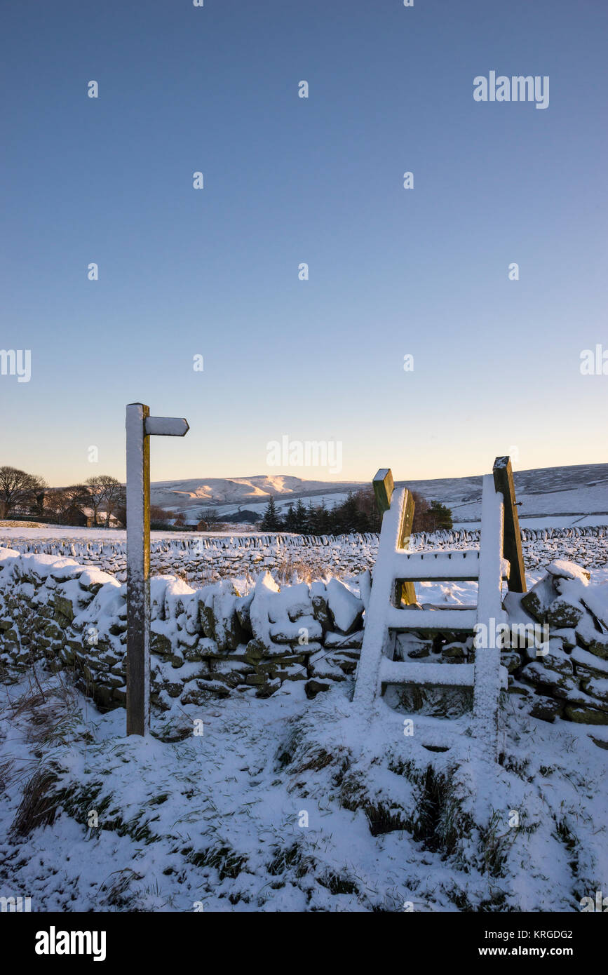 Sentiero segno e stile in legno su un nevoso inverno mattina vicino a Rowarth nel Derbyshire, Inghilterra. Foto Stock