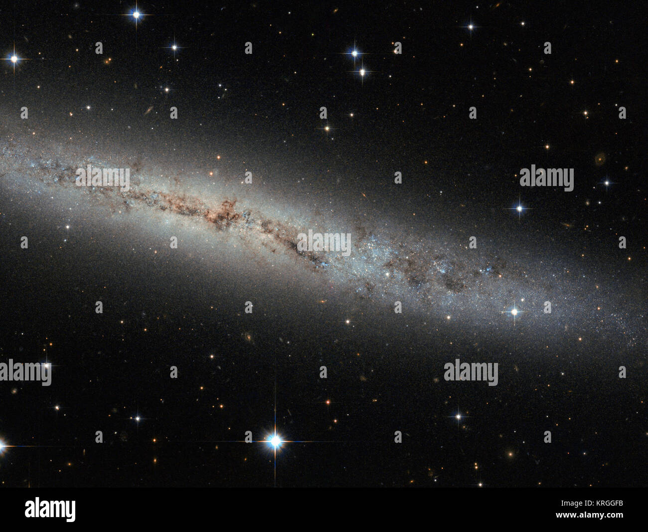 Situato a circa 25 milioni di anni luce di distanza, questa nuova immagine di Hubble mostra galassia a spirale ESO 373-8. Insieme con almeno sette dei suoi vicini galattico, questa galassia è un membro dell'NGC 2997 Gruppo. Lo vediamo side-on come una sottile striscia di scintillanti attraverso il cielo, con tutto il suo contenuto perfettamente allineate sullo stesso piano. Vediamo tante galassie come questa - piana distesa frittelle - che il nostro cervello processo a malapena la loro forma. Ma fermiamoci e chiedete: Perché sono le galassie distesa ed allineato come questo? Provare a girare intorno nella vostra sedia con le gambe e le braccia. Estrarre lentamente le gambe e il braccio Foto Stock